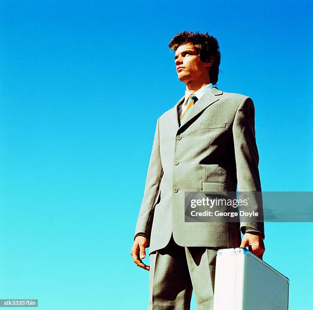 low angle side profile of a businessman carrying a briefcase - cross-entwicklung stock-fotos und bilder