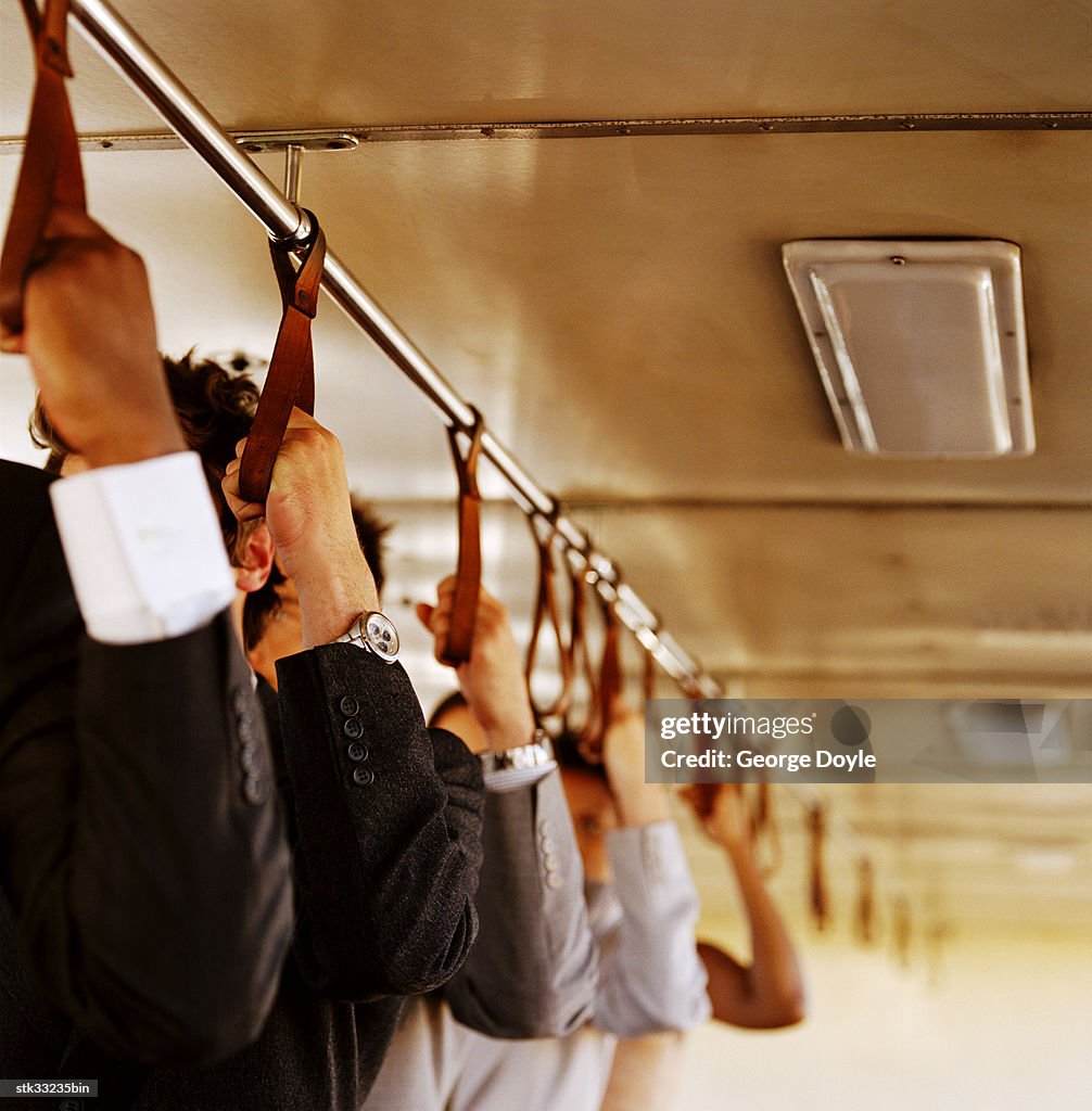 Close-up of hands holding handle straps inside a commuter vehicle