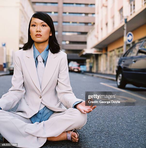 a businesswoman in a yoga pose sitting in the center of the street with eyes open - the center stock pictures, royalty-free photos & images