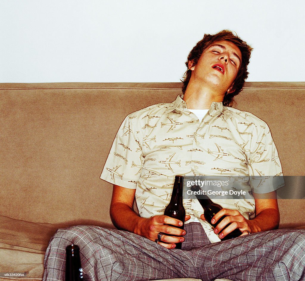 Portrait of a young man asleep on the couch after drinking too much beer
