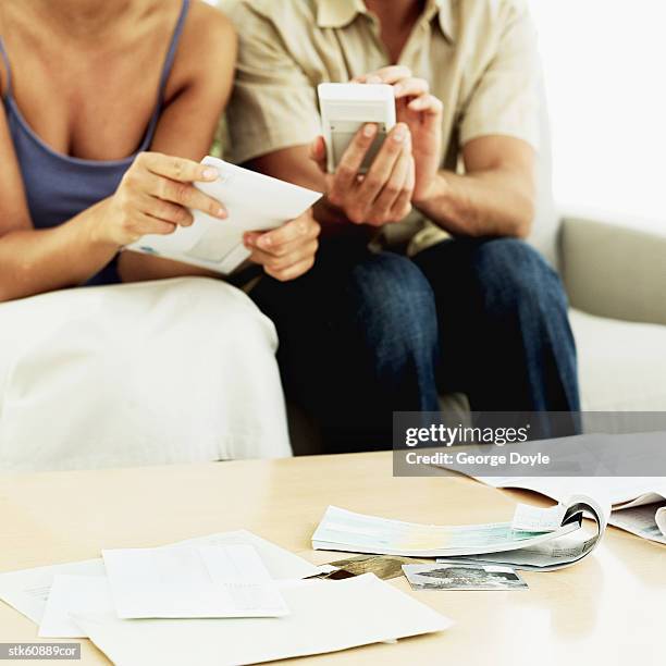 couple sitting on couch doing accounts - duing stock pictures, royalty-free photos & images