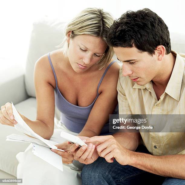 portrait of a young couple sitting together doing accounts - duing stock pictures, royalty-free photos & images