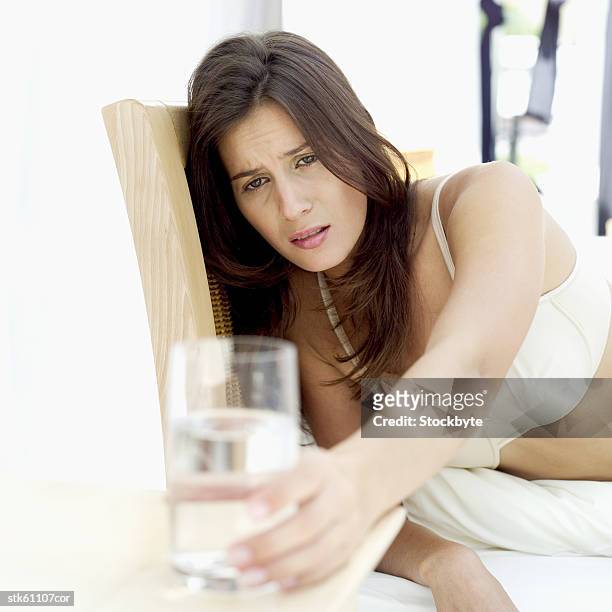 an ill woman lying in bed and reaching out for a glass of water - went out stock pictures, royalty-free photos & images