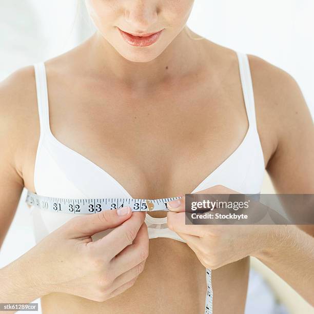 close-up of a woman measuring her chest with an inch tape - inch stock pictures, royalty-free photos & images