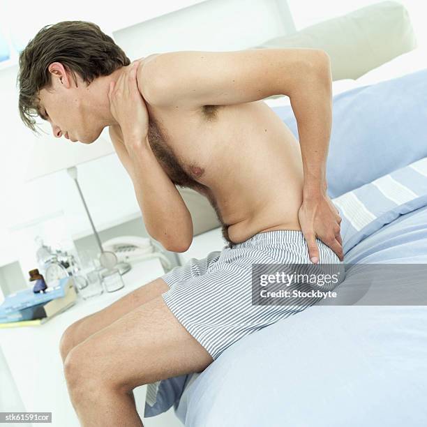 side view of a man with back pain - lesión de latigazo cervical fotografías e imágenes de stock