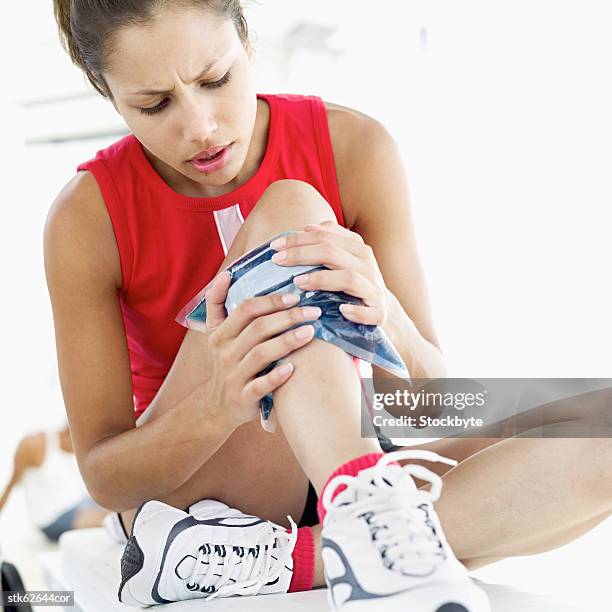 close-up of a woman sitting with an icepack on her leg - compresse stock-fotos und bilder