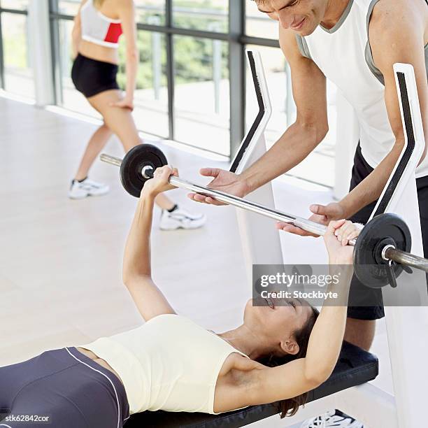 woman lifting a barbell with man helping her - spotting bildbanksfoton och bilder