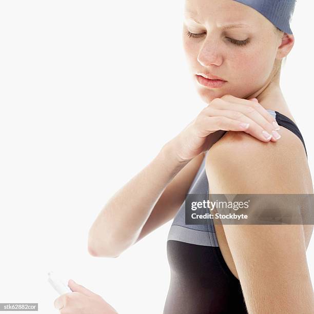 woman applying anti-inflammatory cream to her shoulder - entzündungshemmend stock-fotos und bilder