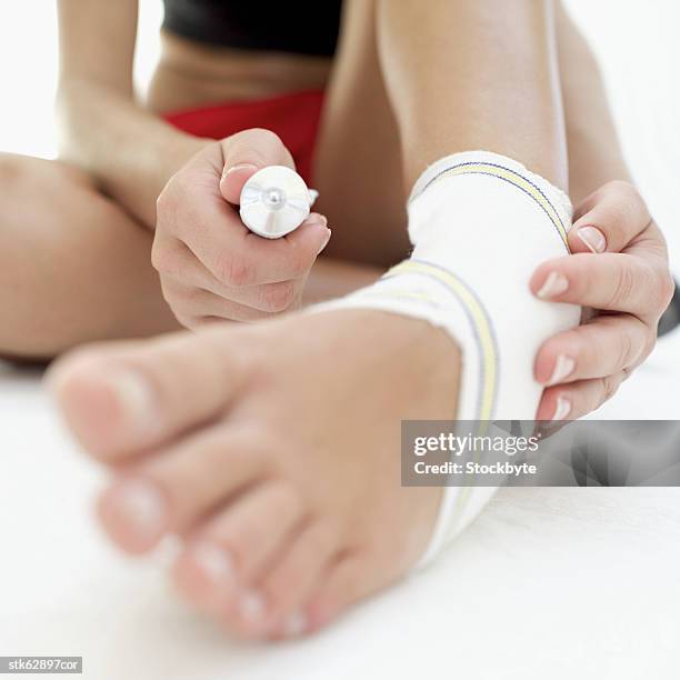 close-up of a woman wearing an ankle support and holding a tube of anti-inflammatory cream - creme tube ストックフォトと画像