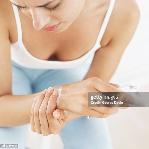 close-up of a woman applying an anti-inflammatory cream to her wrist - articulation-du-corps-humain photos et images de collection