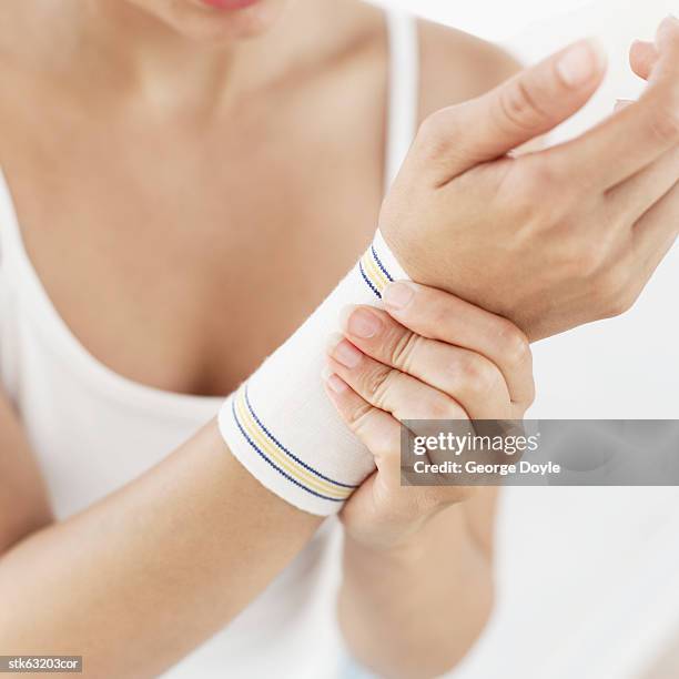 close-up of woman putting on a wrist support - articulation-du-corps-humain photos et images de collection