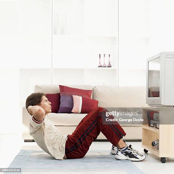 side view of a man doing sit ups on his living room floor - recreational equipment stock pictures, royalty-free photos & images