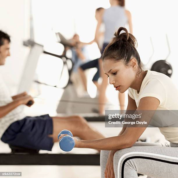 side view of a woman working out with a dumbbell at the gym - went out stock pictures, royalty-free photos & images