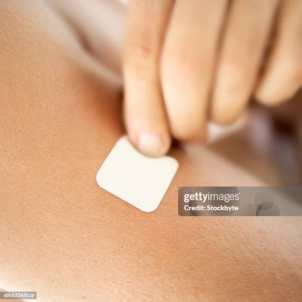 close-up of a person removing a nicotine patch on the arm - smoking patch stock pictures, royalty-free photos & images