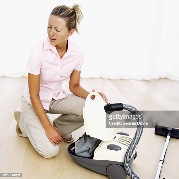 woman cleaning out a vacuum cleaner and sneezing - get out stock-fotos und bilder