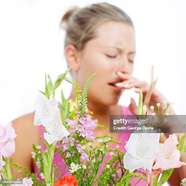 young woman sneezing due to pollen dust from flowers - temperate flower imagens e fotografias de stock