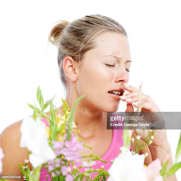 young woman sneezing due to pollen dust from flowers - temperate flower stockfoto's en -beelden