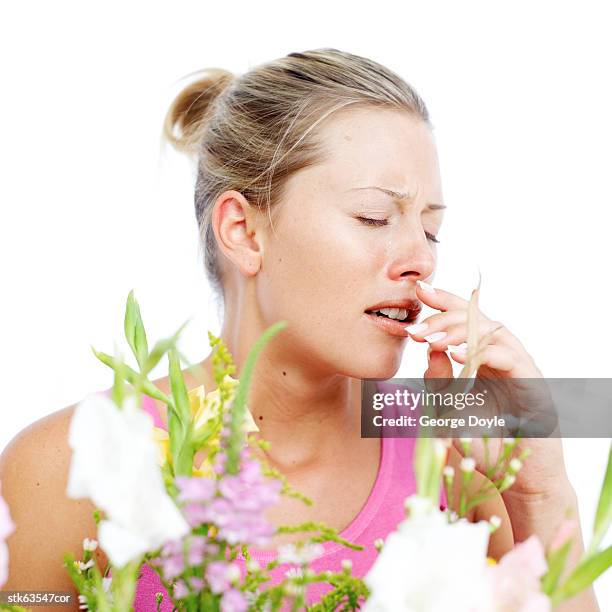 young woman sneezing due to pollen dust from flowers - temperate flower imagens e fotografias de stock