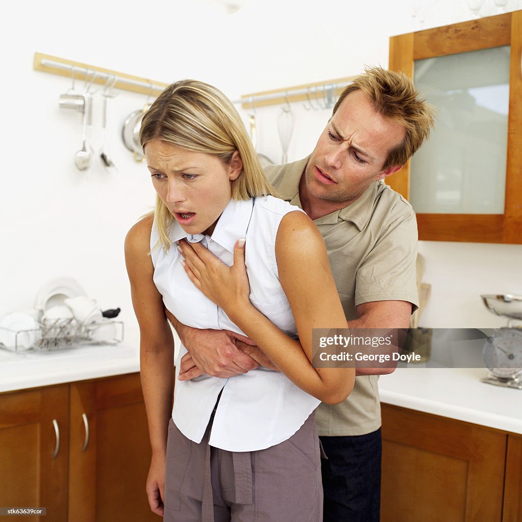 Man performing the Heimlich maneuver on a woman