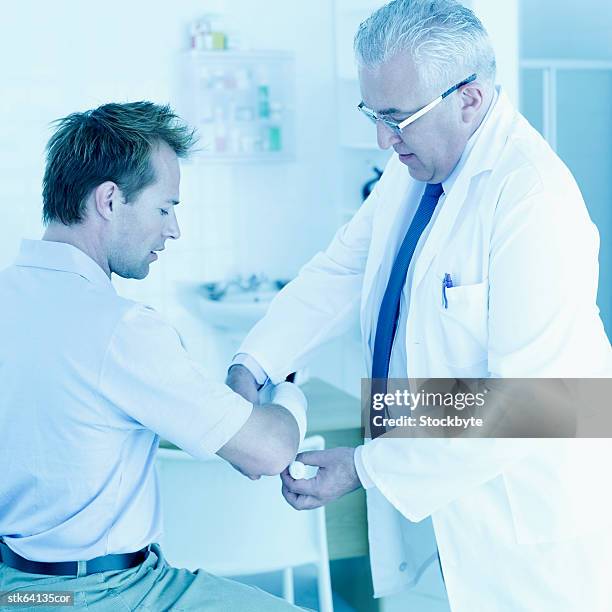 doctor dressing man's hand with bandage - dressing up ストックフォトと画像