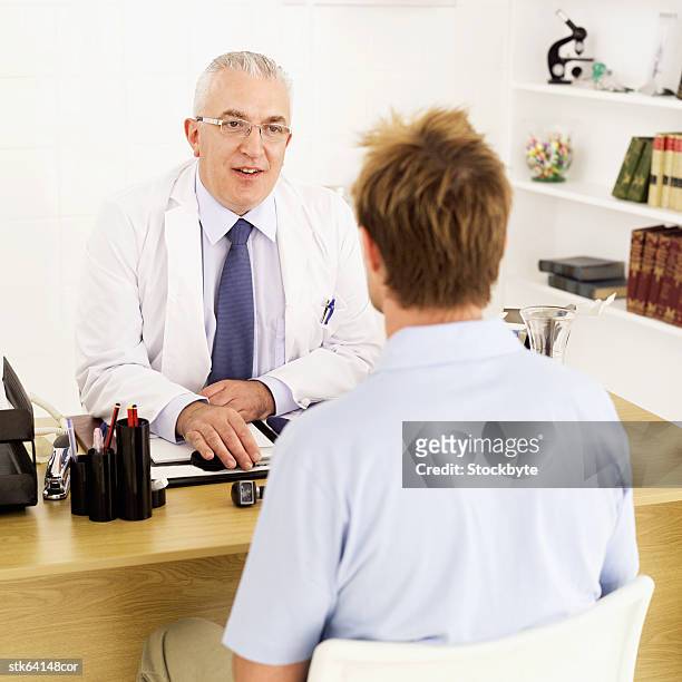 doctor sitting at desk talking to patient - screening of la legende de la palme dor after party at china tang stockfoto's en -beelden