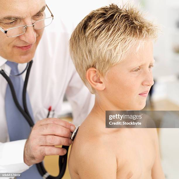 doctor examining a boy with stethoscope - screening of la legende de la palme dor after party at china tang stockfoto's en -beelden