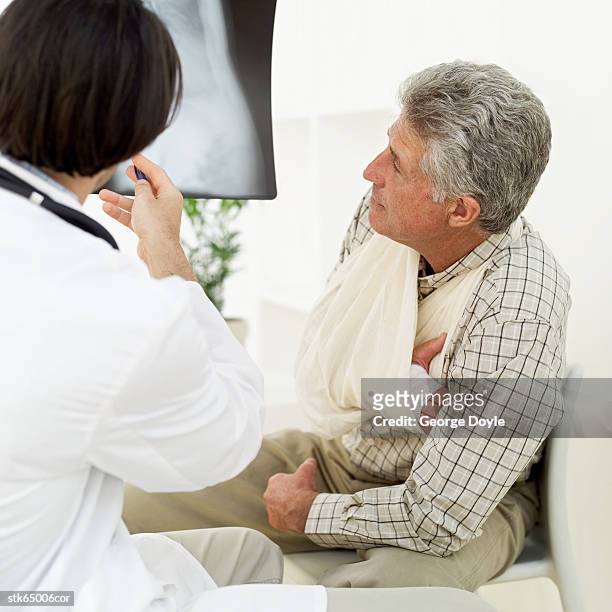 male doctor showing patient an x-ray - screening of la legende de la palme dor after party at china tang stockfoto's en -beelden