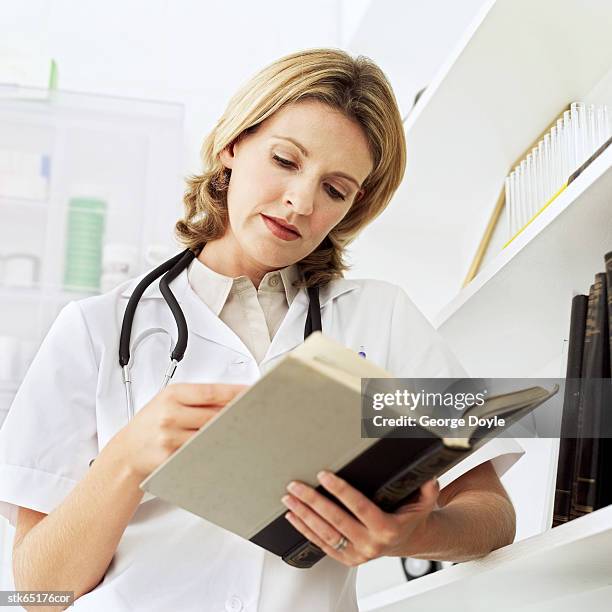 low angle view of a female doctor reading a journal - reference book stock pictures, royalty-free photos & images