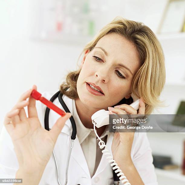 female doctor talking on the telephone with a red test tube in her hand - screening of abramoramas hare krishna the mantra the movement and the swami who started it all arrivals stockfoto's en -beelden