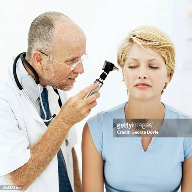 doctor examining patient with an othoscope - screening of la legende de la palme dor after party at china tang stockfoto's en -beelden