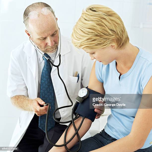 side profile of a doctor checking a young woman's blood pressure - screening of abramoramas hare krishna the mantra the movement and the swami who started it all arrivals stockfoto's en -beelden