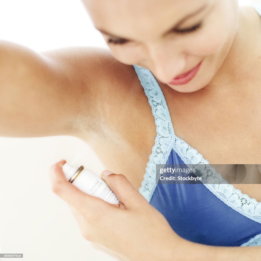 Portrait of a woman spraying deodorant under her arm