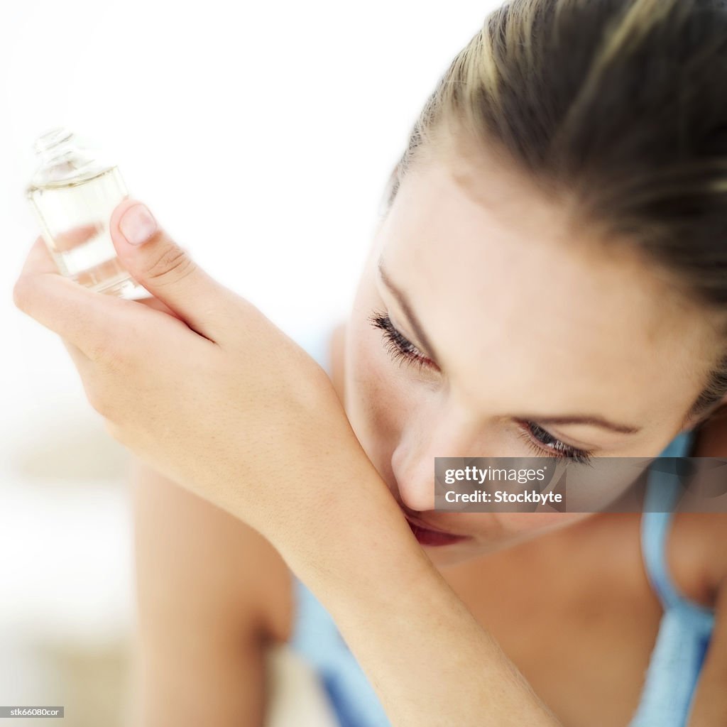 Portrait of a young woman smelling perfume on her wrist