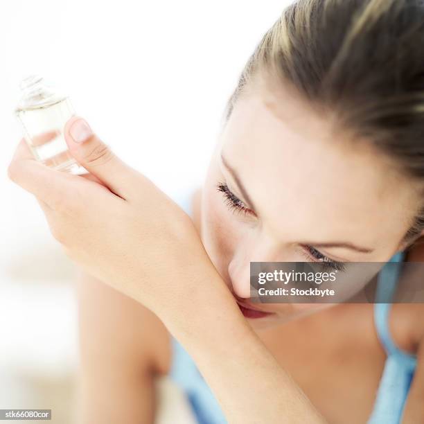 portrait of a young woman smelling perfume on her wrist - wrist stock pictures, royalty-free photos & images