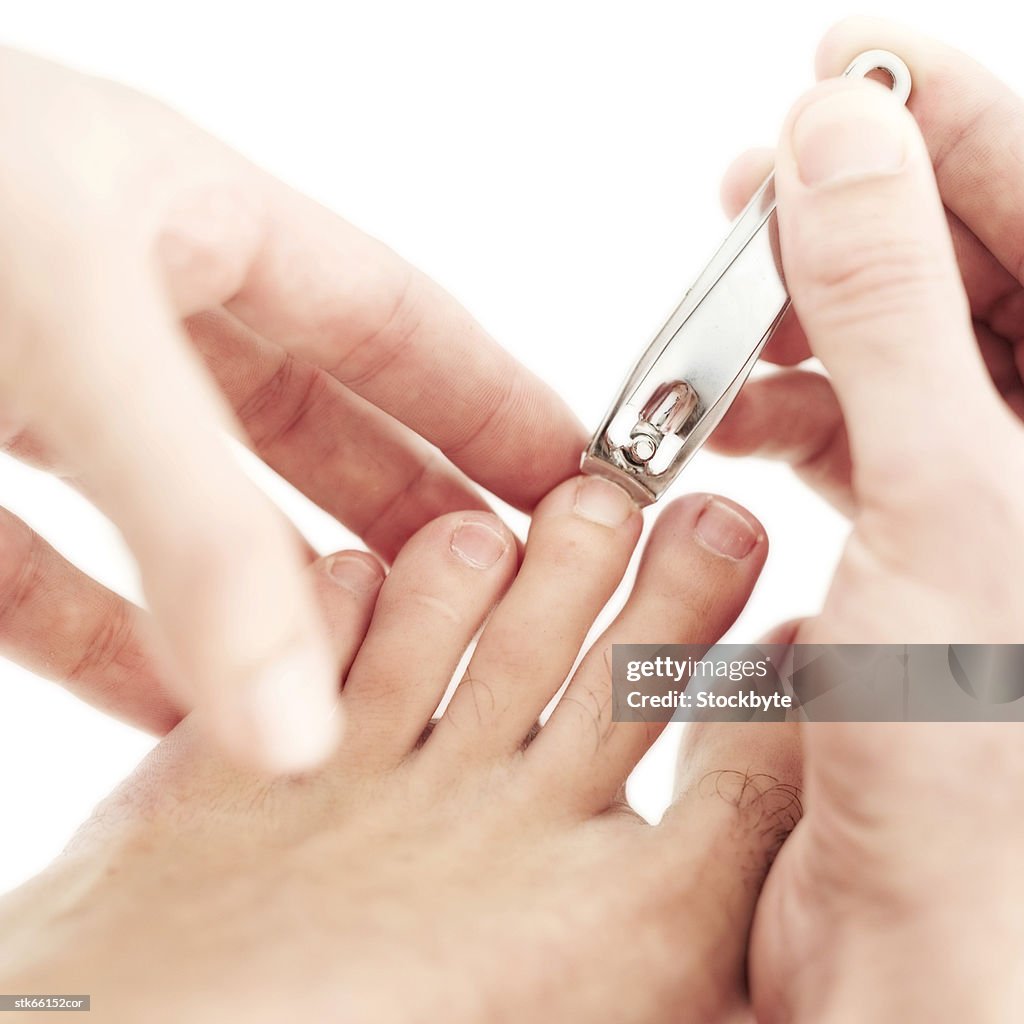 Close-up of hands clipping toenails with a nail cutter