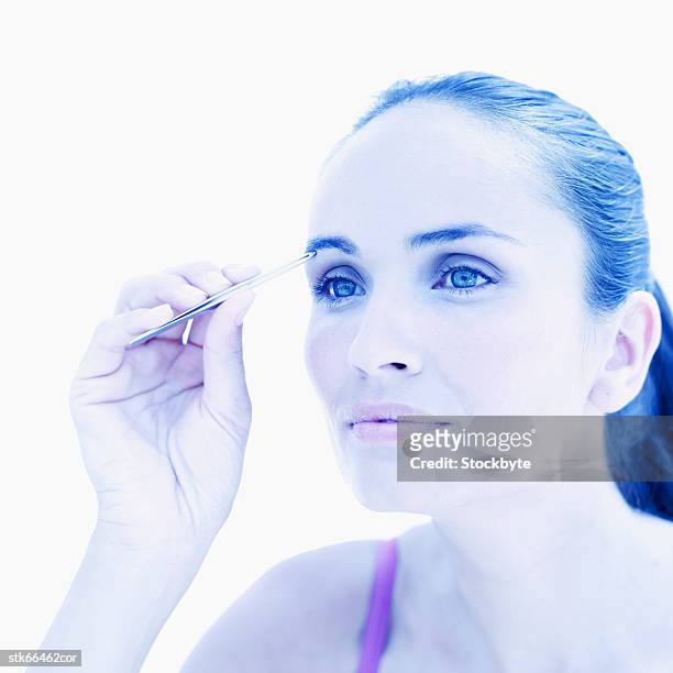 woman plucking her eyebrows - film tungstène photos et images de collection