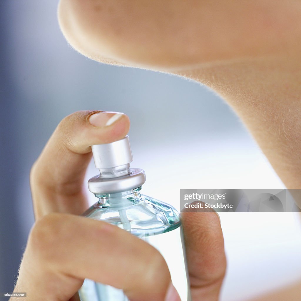 Close-up of a woman about to spray perfume on her neck