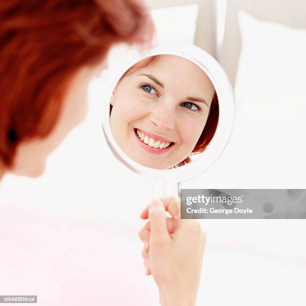 reflection in the mirror of a woman smiling - reflection foto e immagini stock