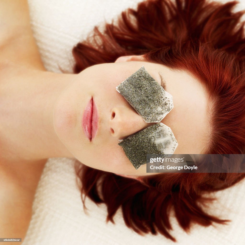 Woman lying with tea bags on her eyes
