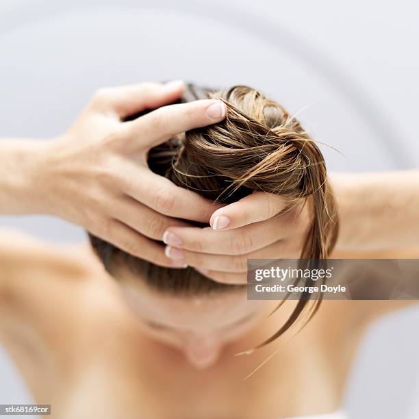 high angle view of a woman piling her hair up into a bun - top of head stock pictures, royalty-free photos & images