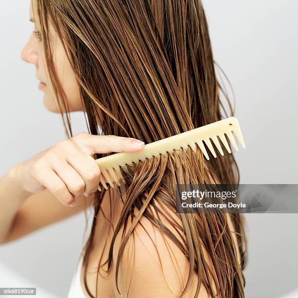 side view of a woman combing her hair - peinar fotografías e imágenes de stock