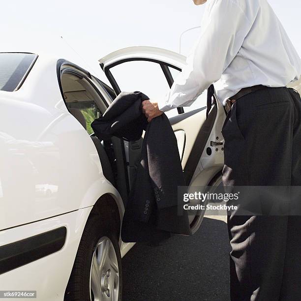 side profile of a businessman putting his jacket into a car - in profile stock pictures, royalty-free photos & images