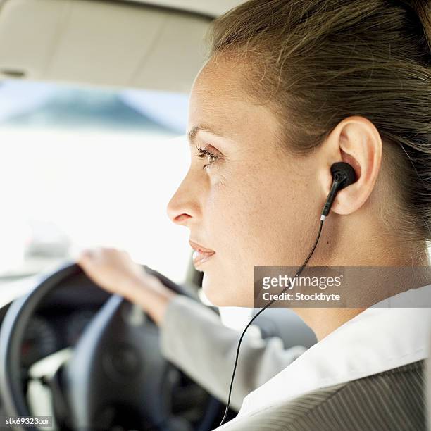 side profile of a businesswoman driving a car and wearing an earpiece - in profile stock pictures, royalty-free photos & images