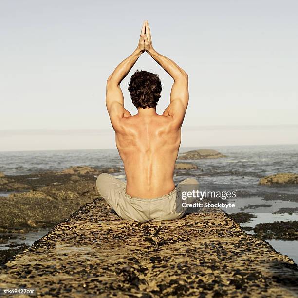 rear view of a man doing yoga - menschliche gliedmaßen stock-fotos und bilder