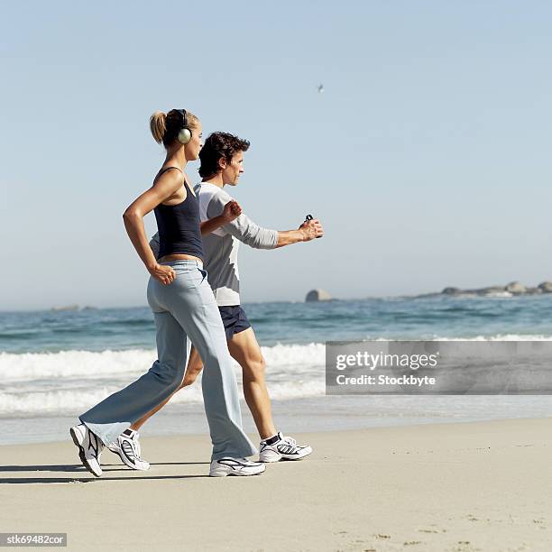 side profile of a couple power walking on the beach - in profile stock pictures, royalty-free photos & images