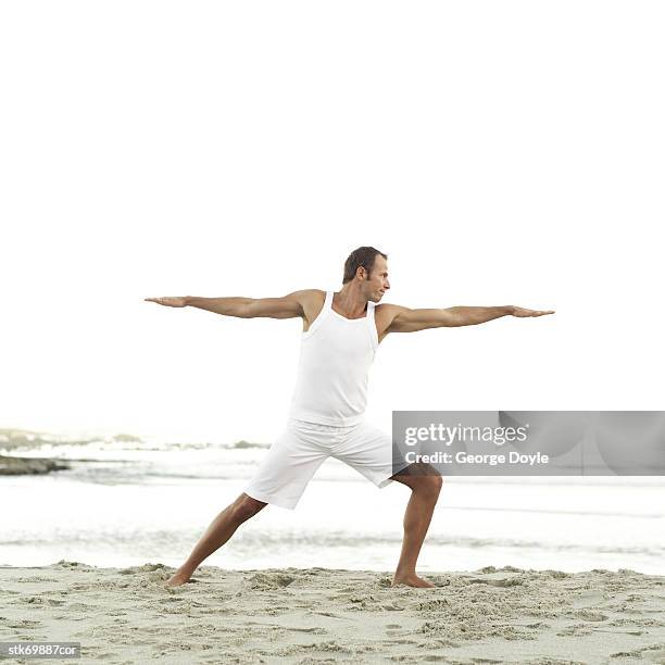 man doing stretching exercises on the beach - duing stock pictures, royalty-free photos & images