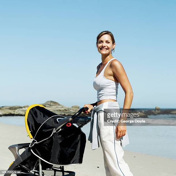 side profile of a woman pushing a stroller on the beach - in profile stock pictures, royalty-free photos & images