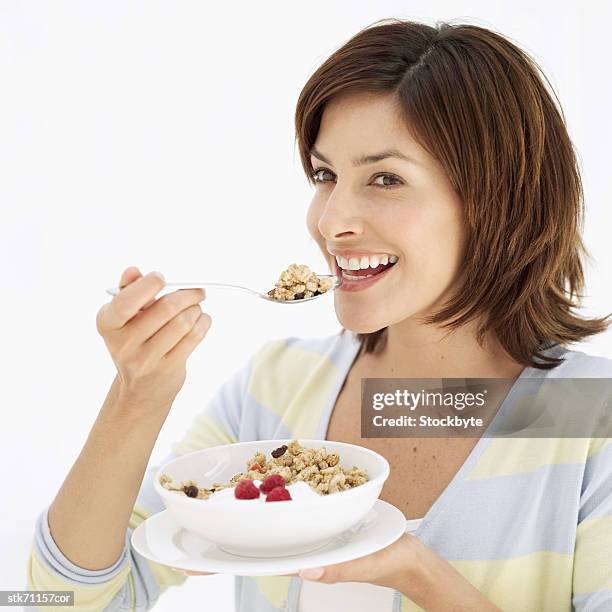 side view of a woman eating a bowl of cereal - spoon in hand stock-fotos und bilder