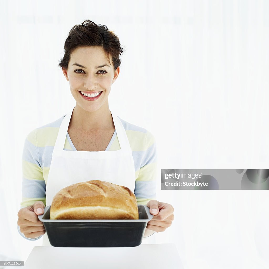 Portrait of a woman holding a baking tray with freshly baked bread