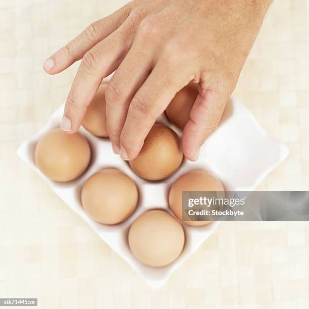 person's hand picking an egg from a crate - organic compound - fotografias e filmes do acervo